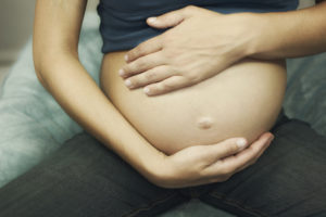 Cropped pregnant woman touching belly
