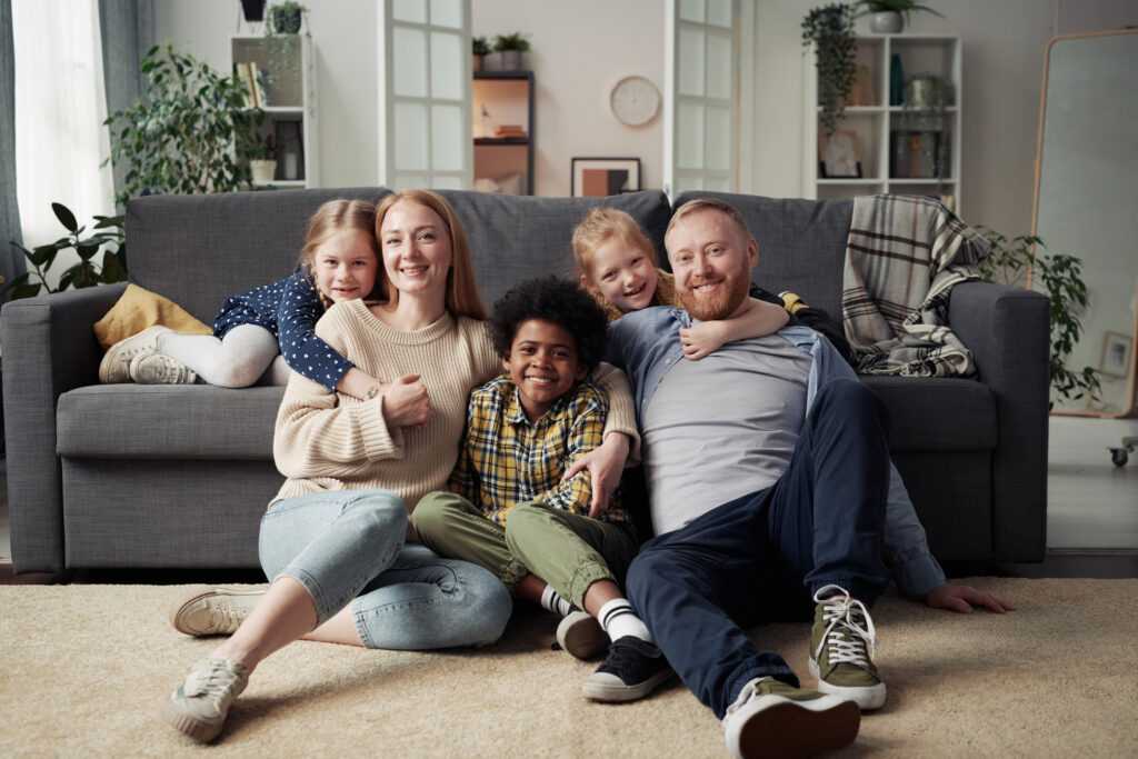 Portrait of happy parents with their adoptive children smiling, highlighting adoption agency services